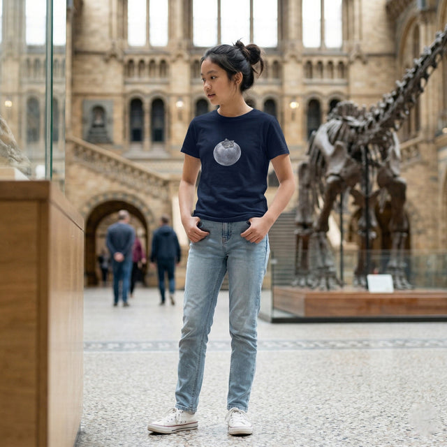 Person wearing a dark blue t-shirt with a graphic design in a museum setting with dinosaur exhibits.