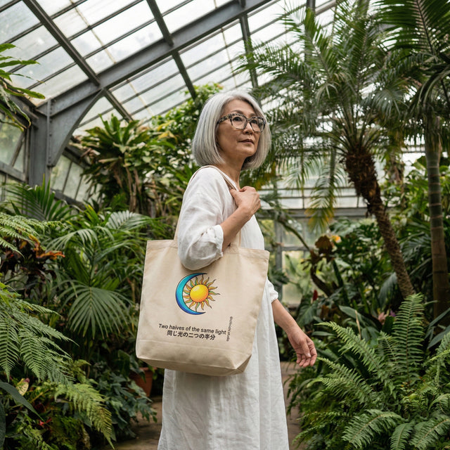 Woman holding a tote bag with a sun design in a greenhouse