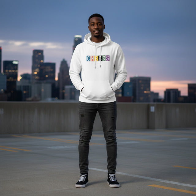 Man wearing a white hoodie with colorful text standing on a rooftop with city skyline in the background