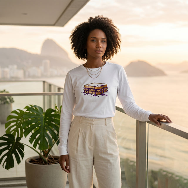 Woman wearing a white long-sleeve shirt with a graphic design, standing on a balcony with a scenic view.
