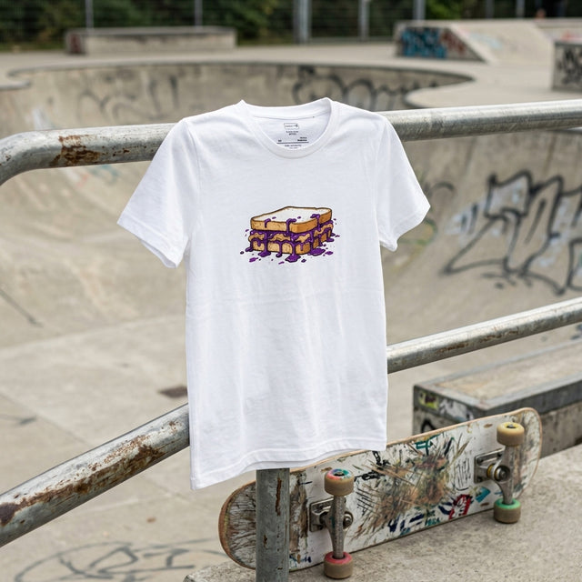 White t-shirt with a graphic design on a metal railing at a skate park.