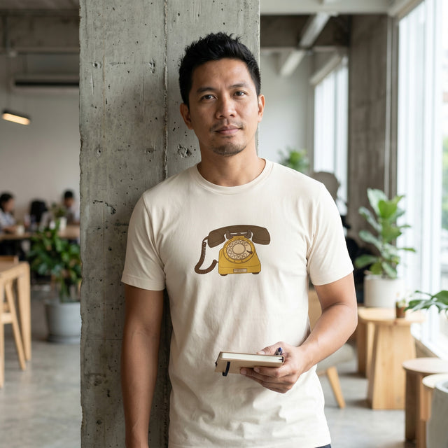 A man in a cafe wearing a t shirt with a rotary phone