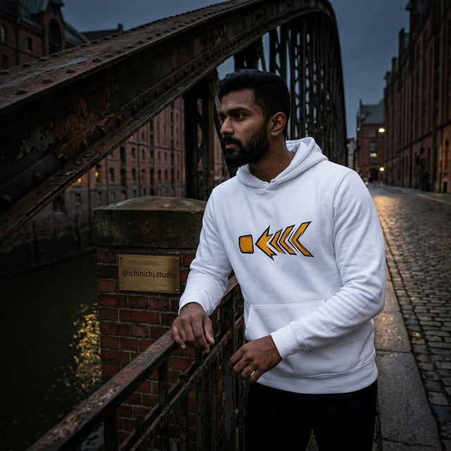 Man wearing a white hoodie with a yellow logo on a bridge at night.