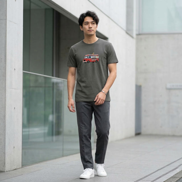 Man wearing a gray t-shirt with a graphic design, standing in front of a modern building.