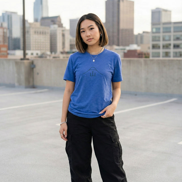 Heather True Royal Blue t-shirt with minimalist Mount Fuji and Kanji design worn by a young woman on an urban rooftop with city skyline.