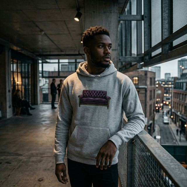 Man wearing a hoodie with a purple couch graphic in an urban setting