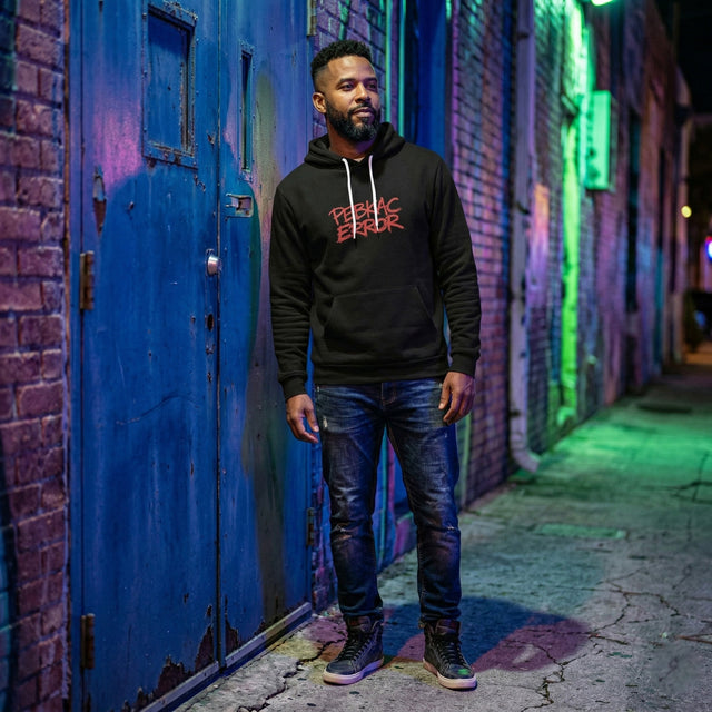 Man wearing a black hoodie with red text in a neon-lit alleyway