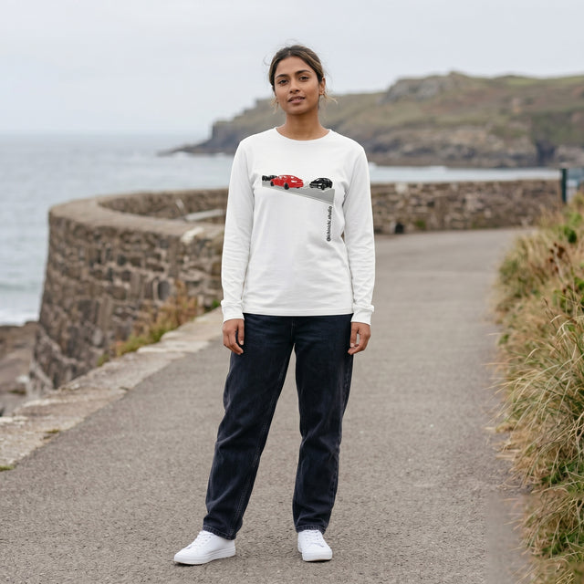 Person wearing a white sweatshirt with a graphic design, standing on a coastal path.