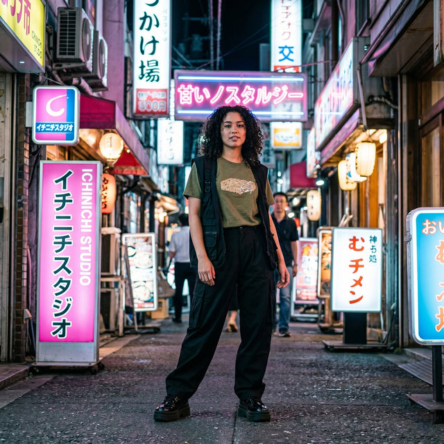 Woman standing in a neon-lit street with various signs in a cityscape