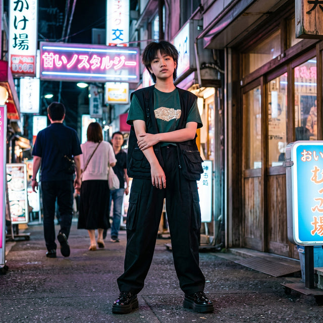 Person standing on a street with neon signs and pedestrians in the background