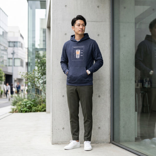 Man wearing a navy hoodie with a graphic design, standing against a modern building.