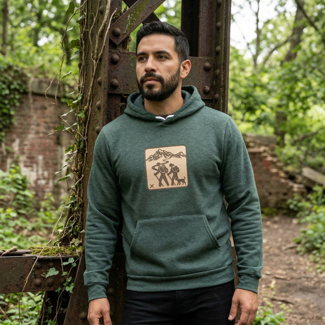 Man wearing a green hoodie with a mountain design in a forest setting