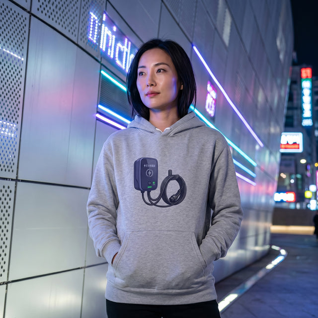 Person wearing a gray hoodie with a design in an urban night setting