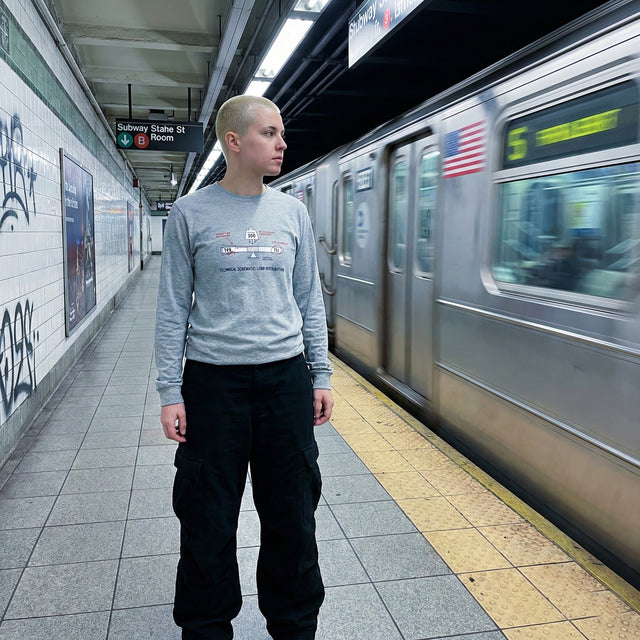 Person standing on a subway platform with a train arriving in the background