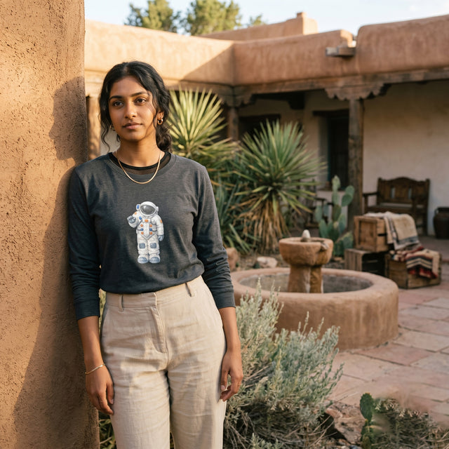 Woman standing in front of a rustic building with cacti and a fountain.