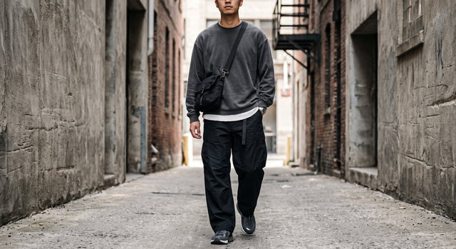 Close-up of layered monochrome streetwear outfit in an urban alley.