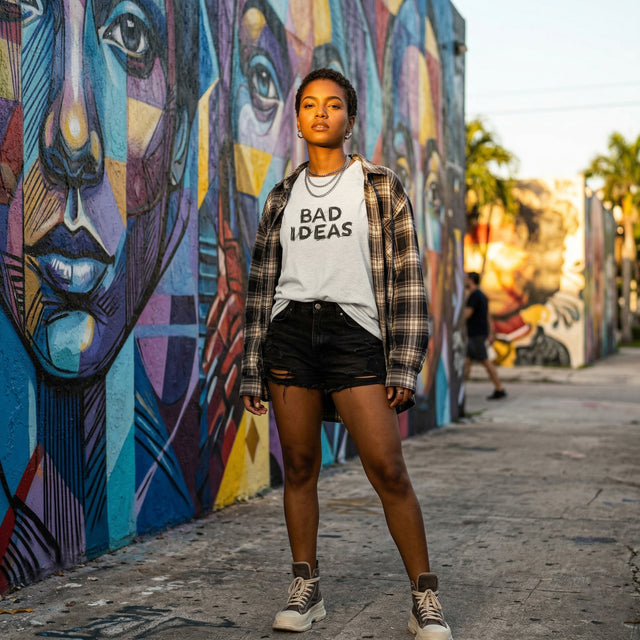Person wearing a 'Bad Ideas' shirt standing in front of colorful murals.