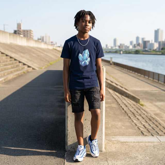 Person wearing a dark blue t-shirt with a graphic design, standing by a river with city skyline in the background.