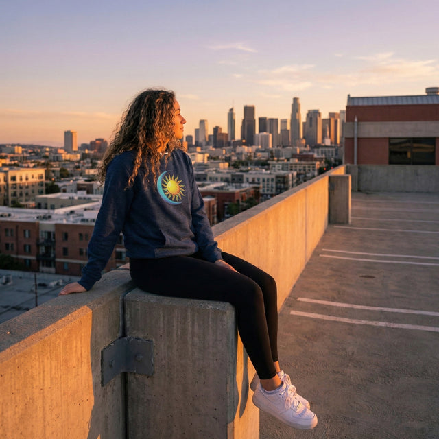 Person sitting on a rooftop with a city skyline in the background during sunset.