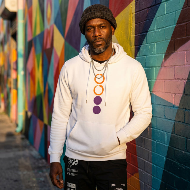 Man wearing a white hoodie with colorful abstract mural in the background