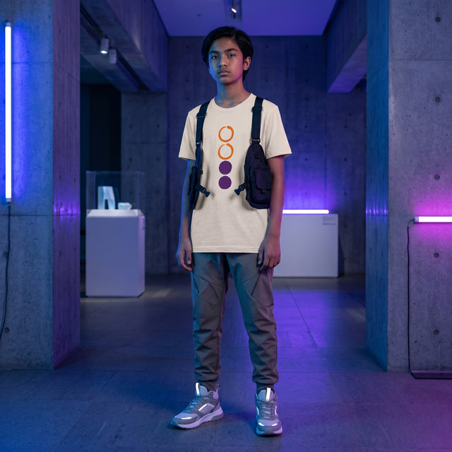 Person wearing a beige t-shirt with colorful design, standing in a futuristic indoor setting with blue and purple lighting.