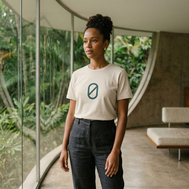 緑が映えるモダンな室内で、ロゴ入りの白いTシャツを着た女性