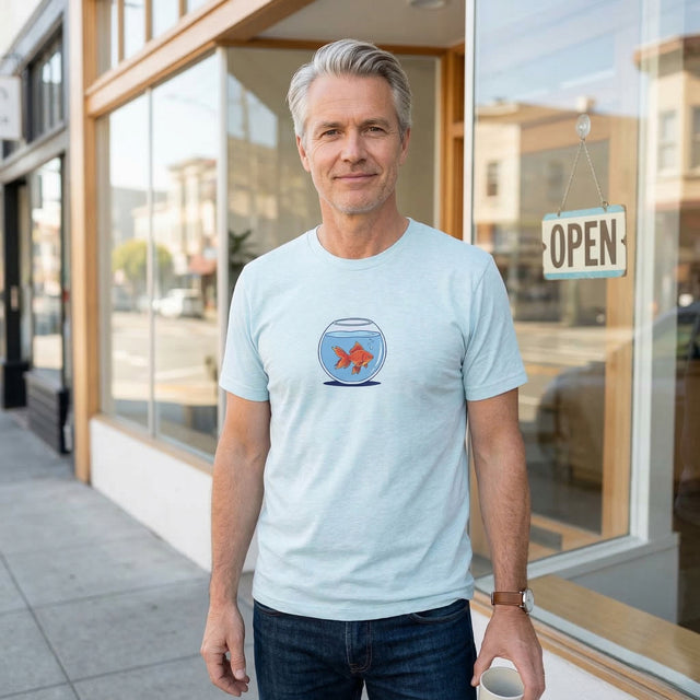 Man wearing a light blue t-shirt with a fishbowl graphic standing in front of a store.