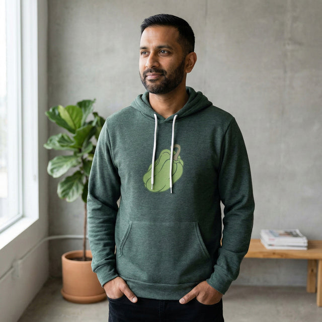 Man wearing a green hoodie with a logo in a room with a plant and table.