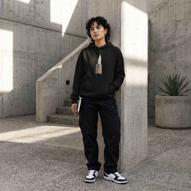 Person wearing a black hoodie and pants standing in a concrete architectural setting