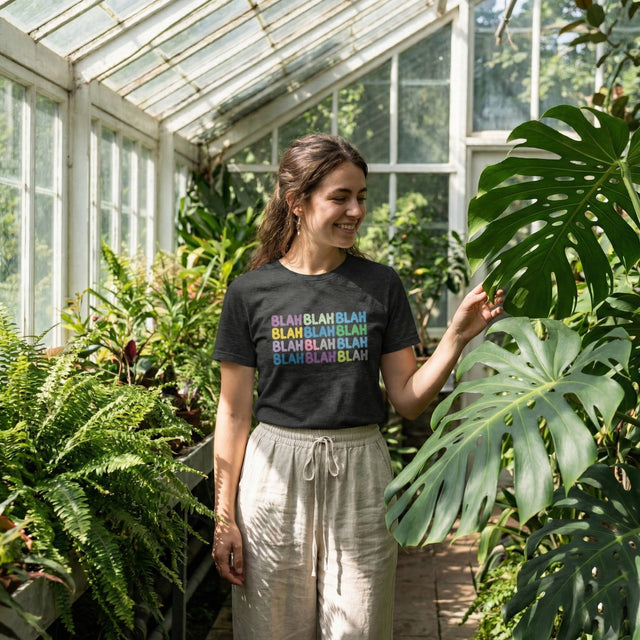 Woman wearing a black t-shirt with colorful text in a greenhouse