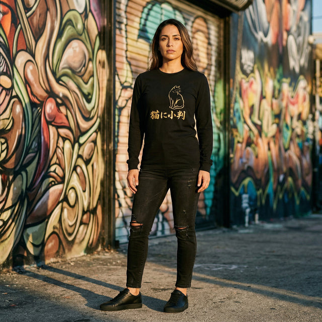 Person wearing a black sweatshirt with a graphic design in front of colorful graffiti art.