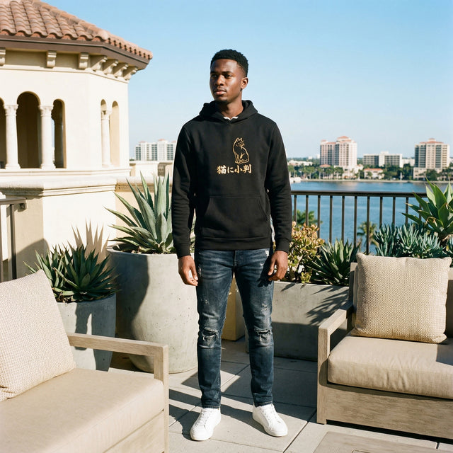 Person wearing a black hoodie with a logo on a rooftop with a cityscape in the background