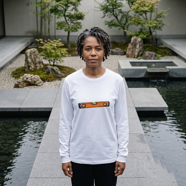Person wearing a white long-sleeve shirt with a design in a garden setting