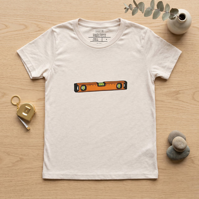 White t-shirt with a level design on a wooden surface with decorative items.