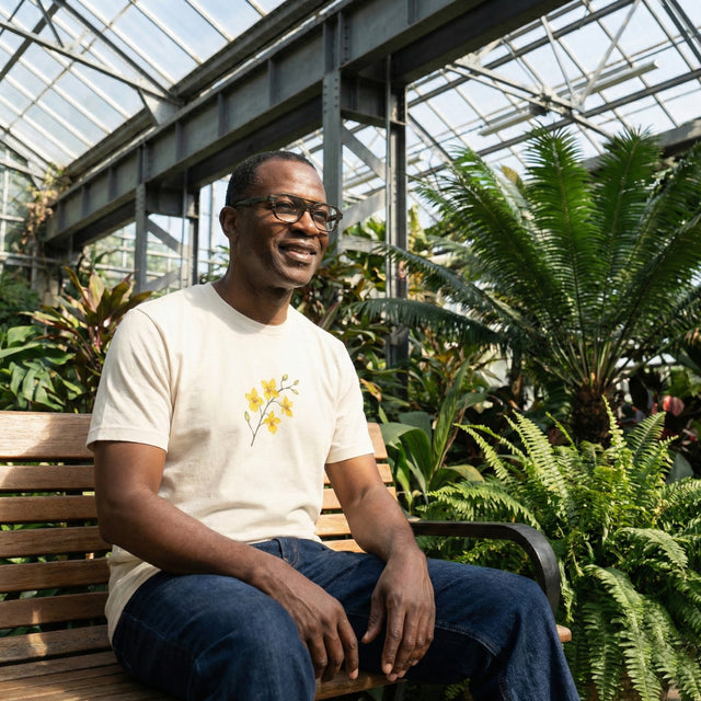 Man sitting on a bench in a greenhouse surrounded by plants