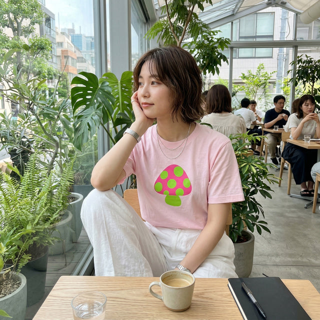 Woman sitting at a table in a cafe with plants and other patrons in the background