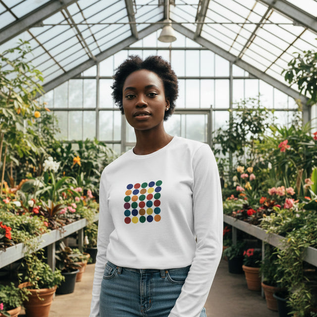Person wearing a white sweatshirt with a colorful square design in a greenhouse setting
