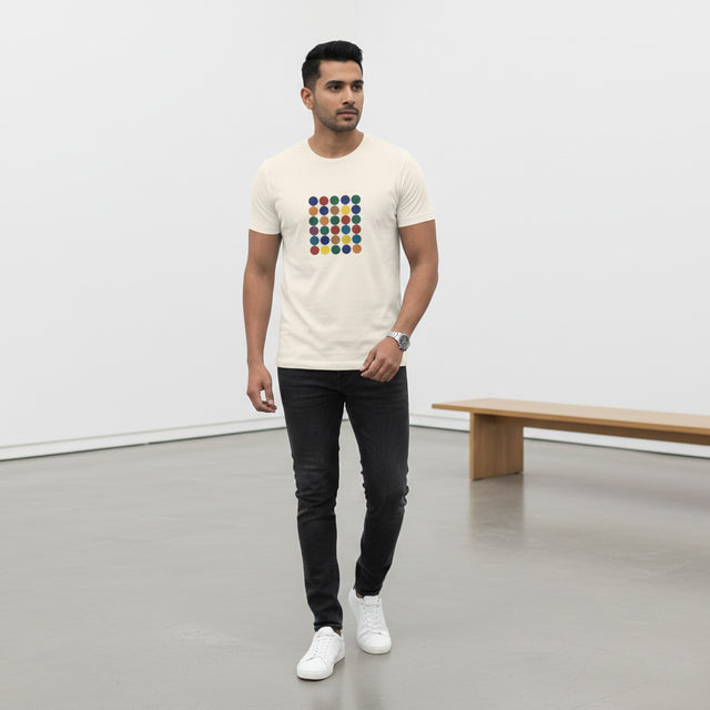 Man wearing a white t-shirt with a colorful geometric design in a minimalistic room.