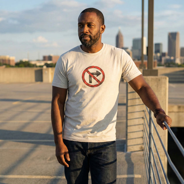 ICHINICHI unisex staple t-shirt in heather dust beige featuring a distressed red and black no right turn traffic sign graphic, modeled in an urban rooftop setting for streetwear fashion.