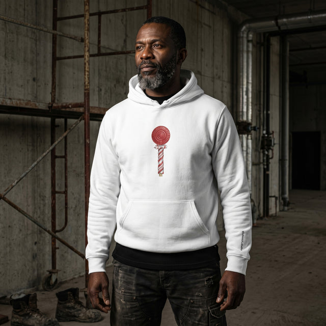 Man wearing a white hoodie with a red and white lollipop design in an industrial setting