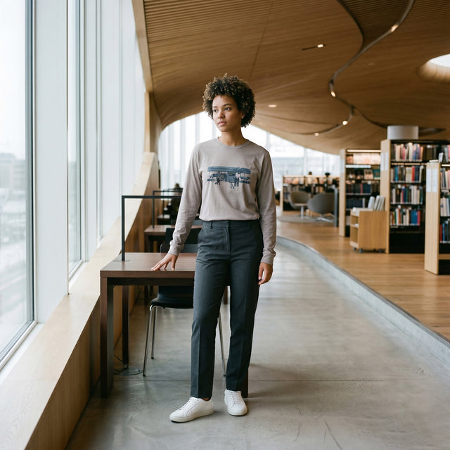 Person standing in a modern library with large windows and bookshelves.