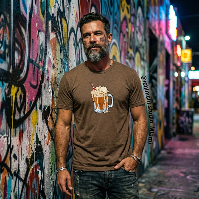 Man wearing a brown t-shirt with a graphic design of a beer mug against a graffiti-covered wall.