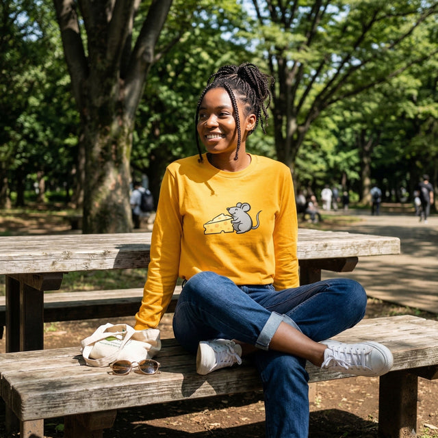 公園の木製のベンチに座っている女性。グラフィック柄の黄色いシャツを着ている。