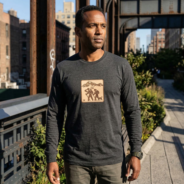Man wearing a dark gray long-sleeve shirt with a logo on a city street