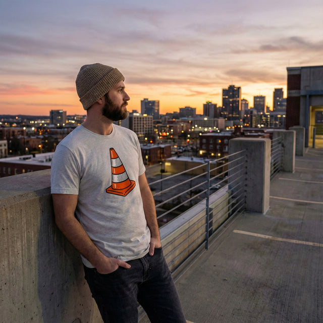 Man wearing a t-shirt with a traffic cone design on a rooftop at sunset.