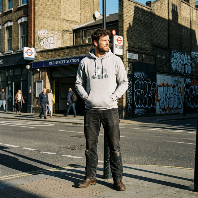 Man standing on a street corner in an urban setting with graffiti on buildings.
