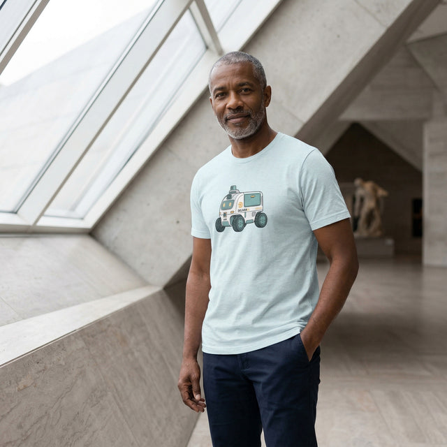 Man wearing a light blue t-shirt with a graphic design, standing in a modern indoor setting.