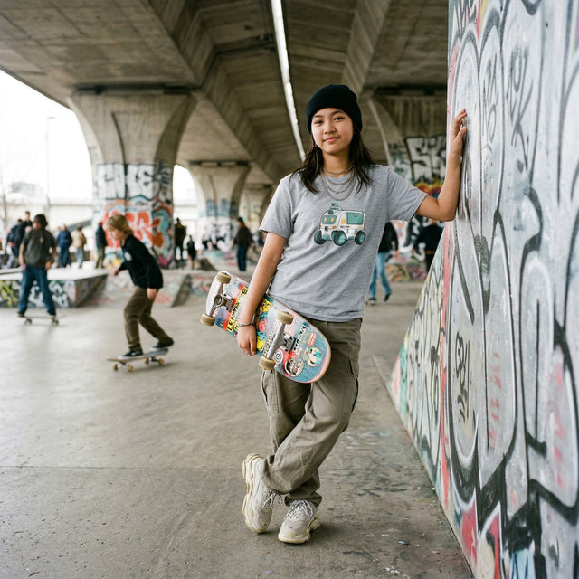 Person holding a skateboard in an urban setting with graffiti on walls