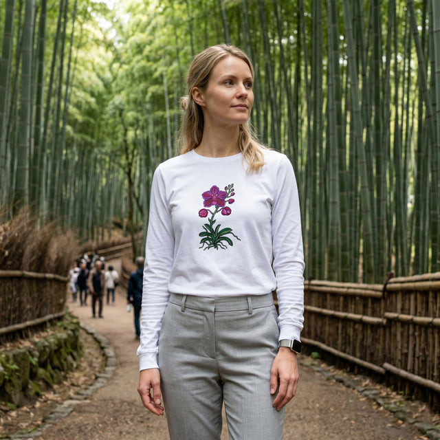 Woman wearing a white long-sleeve shirt with a floral design in a bamboo forest.