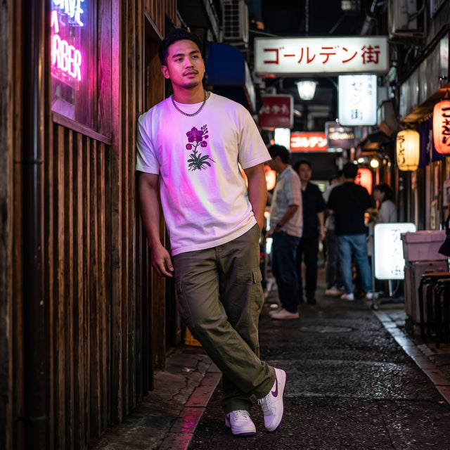 Man standing on a street with neon signs and people in the background